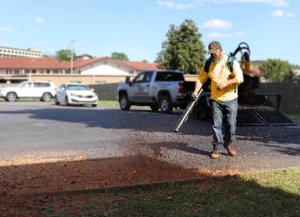 Stump Busters employee blowing wood chips after stump grinding